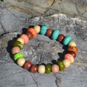 A bracelet of various colored beads on a rock.